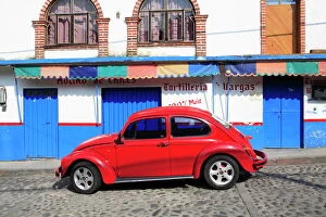 Red Volkswagen Beetle parked on cobblestone street, Tepoztlan, near Mexico City where many city dwellers spend weekends