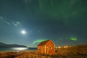 Ramberg Prints: Red wood cabin on sand beach lit by moon during the Aurora Borealis (Northern Lights)