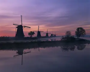 Kinderdijk Prints: Reflections of a line of windmills in a misty landscape at Kinderdjik