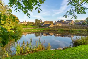 Cottages Prints: Reflections of Monyash village in a pond during autumn in Bakewell