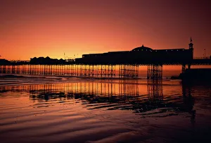 Sussex Prints: Reflections in the sea of the pier at Brighton at sunset, Sussex, England