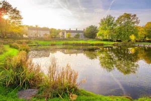 Stillness Prints: Reflections in a village pond at Monyash during autumn with buildings and trees in view