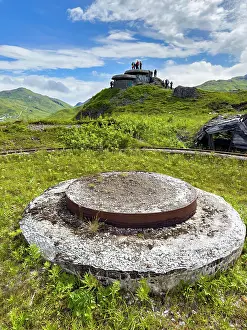 Dutch Prints: Remains of a World War II gun emplacement in an abandoned site with visitors exploring on top in Unalaska Alaska