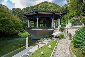 Walkway Prints: Remodeled train station viewed from the riverbank in New Athon with surrounding greenery and mountain backdrop