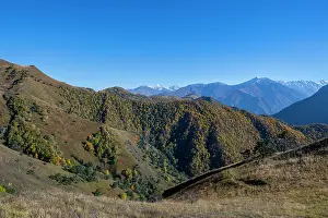 Bright Prints: Remote mountain landscape shows rolling hills and distant snow-capped peaks in Chechnya