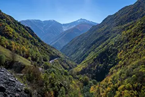 Bright Prints: Remote mountain scenery showcases autumn colors in the Caucasus region of Russia with a clear blue sky above the peaks