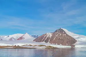 Antarctic Prints: Research base on Stonington Island in Antarctica overlooks melting glaciers and rugged mountains under blue sky