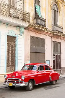 Automobile Prints: Restrored red American car pakred outside faded Colonial buildings, Havana
