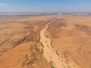 A river bed, palms, and dunes surround the village of Kamour, Mauritania, Sahara Desert, West Africa, Africa