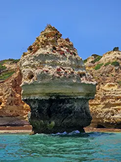Geological Prints: Rocky cliffs rise from clear waters along the Algarve coast on a sunny day in Portugal