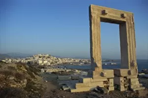 Roman arch at archaeological site with sea and village in the background