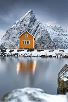 Nordland Gallery: Rorbu in the snow at foot of Olstind mountain overlooking the Arctic Sea, Sakrisoy, Reine