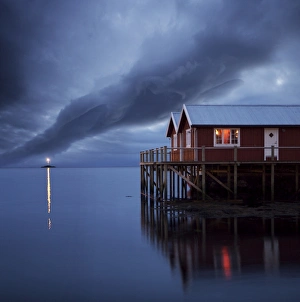 Stilt Prints: Rorbuer on stilts at dusk with lighthouse, Lofoten Islands, Norway, Scandinavia, Europe