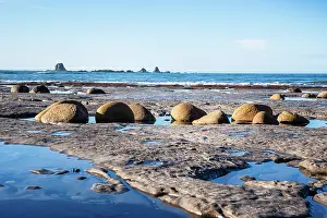 Rounded Prints: Rounded boulders on Cape Foulwind beach at low tide near Tasman Sea and West Coast cliffs in South Island New Zealand