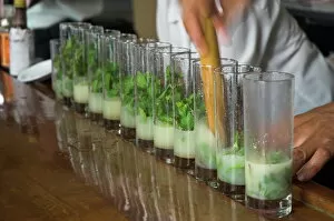 Eating And Drinking Collection: Row of glasses on a bar with barman preparing mojito cocktails, Habana Vieja