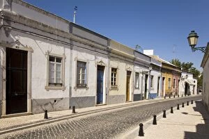 A row of traditional cottages front a cobbled street in the walled town of Faro