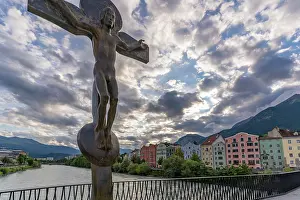 Innsbruck Prints: Rudi Wach Kreuz sculpture stands on a bridge with buildings and clouds at sunset in Innsbruck