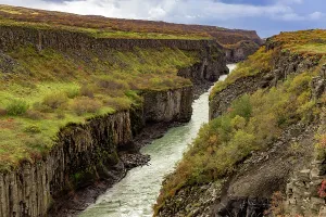 Volcanic Prints: Rugged cliffs and autumn colors in Hvit River Canyon with river flowing through layers of volcanic rock in Iceland