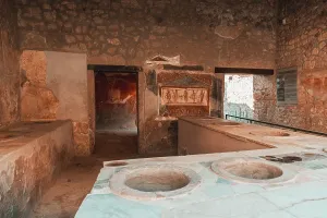 Management Prints: Ruins of ancient Pompei showing kitchen area with stone features and wall paintings in Italy's historical site