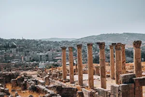 Jerash Prints: The ruins of a Roman temple, with the modern city of Jerash in the background