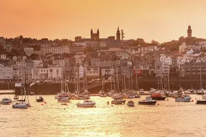Sailboats Prints: Sailboats are moored in St Peter Port Harbour during sunset with the skyline of Guernsey in the background