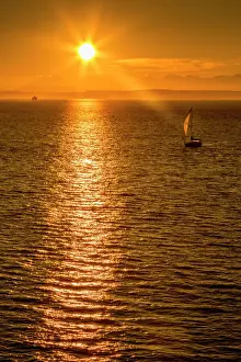 Glowing Prints: Sailing boat and sunset over Elliott Bay with Bainbridge Island visible on the horizon