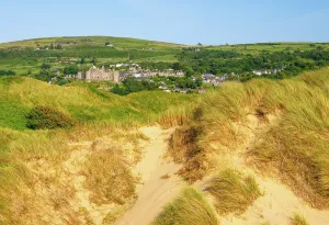 Gwynedd Prints: Sand dunes and Harlech Castle visible in background with town of Harlech nestled in hills during clear weather