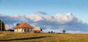 Fence Prints: Scenic rural house set against the sky in a remote mountain village of Romania during the day