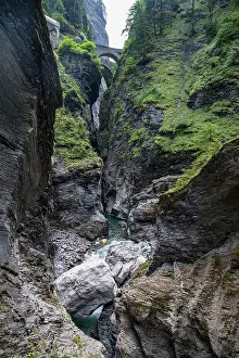 Trail Prints: Scenic view of the gorge with a stone bridge and flowing river in Switzerland's mountainous landscape