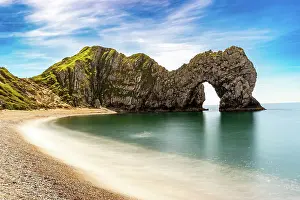 Enjoy Prints: Scenic view of a natural arch on a coastline with a sandy beach and clear blue sky at Durdle Door