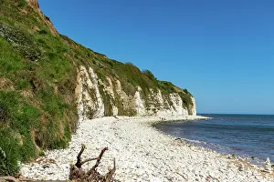 White Cliffs Prints: Scenic view of a white chalk cliff by the sea with a pebble beach under a clear blue sky