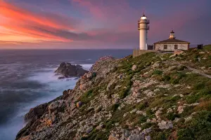 Sea landscape view of Cape Tourinan Lighthouse at sunset with pink clouds, Galicia, Spain
