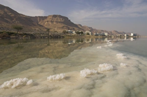 Sea and salt formations with hotels and desert cliffs beyond