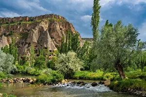 Cappadocia Prints: Selime houses sit by a river in Ihlara valley surrounded by trees and cliffs in Cappadocia Turkey