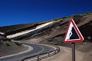 Attention Prints: Sign on road with stratified volcanic rocks in the background, Parque Nacional del Teide