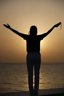 40 45 Years Prints: Silhouette of faithful woman praying with rosary beads at sunset as concept for religion
