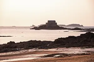 Grand Prints: Silhouette of Grand B tidal island and ancient fort against a pastel sunset sky in Saint Malo