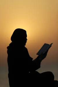 Quran Prints: Silhouette of a Muslim woman reading the Noble Quran at sunset, United Arab Emirates