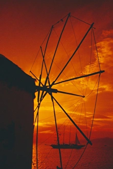 Silhouette of a windmill at sunset and boat in the background