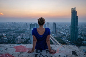 Graffiti Prints: A single woman watching sun set over city skyline at dusk