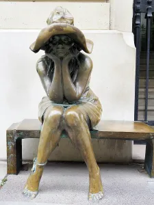 Stillness Prints: Sitting figure in bronze hat resting on a bench outside the Institut Liszt in Paris