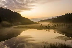 Swamp Prints: Sky painted orange at dawn with misty land of Pian di Gembro nature Reserve, aerial view
