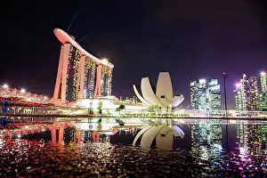 Rain Prints: Skyline of Singapore Marina Bay at night with Marina Bay Sands and Art Science museum reflecting in a pond after rain