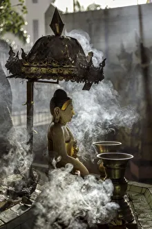 Vase Prints: A small Buddha statue at Sule pagoda, surrounded by clouds of smoke with two Kinaree