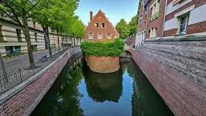 Channel Prints: Small channel surrounded by buildings and green plants in Amiens offers a view of the waterway