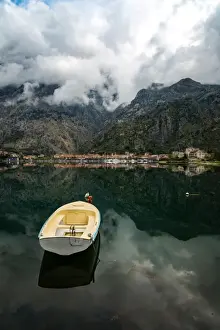 Montenegro Prints: A small fishing boat sits in the reflection of the Old Town (stari grad) of Kotor in Kotor Bay
