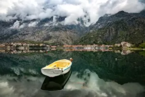 A small fishing boat sits in the reflection of the Old Town (stari grad) of Kotor in Kotor Bay