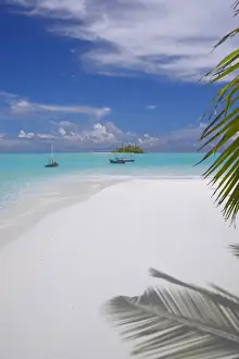 Small fishing boats (dhoni) in clear water and remote island in background
