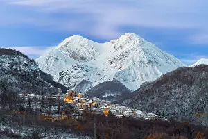 The small illuminated village of Pietracamela covered with snow and surrounded by Intermesoli snowy peak at dusk, Gran Sasso and Monti della Laga National Park, Apennines, Teramo district, Abruzzo region, Italy, Europe