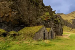 Adventures Prints: Small stone turf hut under rugged lava cliff shows traditional Icelandic craftsmanship near Seljalandsfoss in Iceland